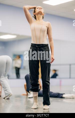 Ballerina stretching neck during dance studio rehearsal Stock Photo
