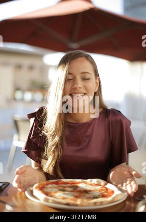 Happy young woman smiling with eyes closed over pizza Stock Photo