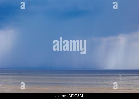 Distant rain falling over the calm Baltic Sea surface in Jurmala, Latvia Stock Photo