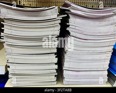 Neatly stacked magazines with colorful covers and white pages on a shelf in a retail store, displaying various titles and designs for customers Stock Photo