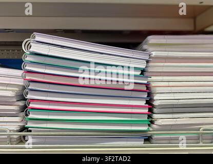 Colorful notebooks with spiral bindings are stacked on a shelf in a stationery store, featuring a mix of pastel and vibrant colors Stock Photo