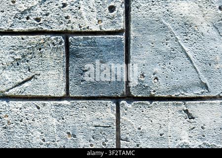 Close-up of textured grey stone blocks with pitted surface. Modern architectural background for construction and urban design projects Stock Photo