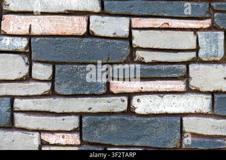Multicolored stone wall with blue, grey, and peach bricks. Textured masonry background for architectural and construction design projects Stock Photo