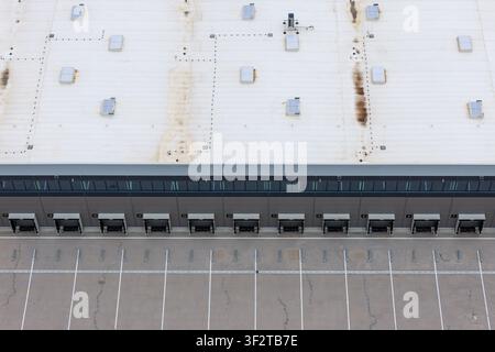 Aerial view of a large distribution hub featuring multiple loading docks and a spacious parking lot with marked bays, Poland. Stock Photo