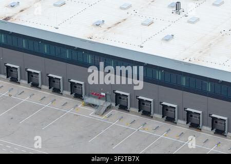 Aerial view of a large distribution hub featuring multiple loading docks, a paved parking area with marked spaces, and a modern industrial warehouse b Stock Photo