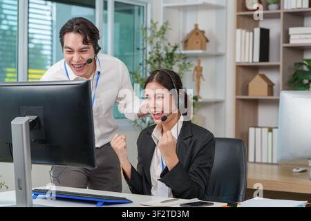 Excited Asian business colleagues celebrating success in call center office Stock Photo