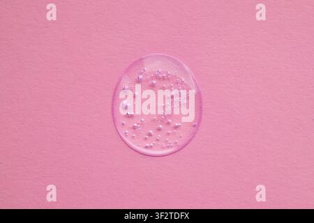 Close-up of clear serum droplet with bubbles on pink background for skincare and cosmetic concept Stock Photo