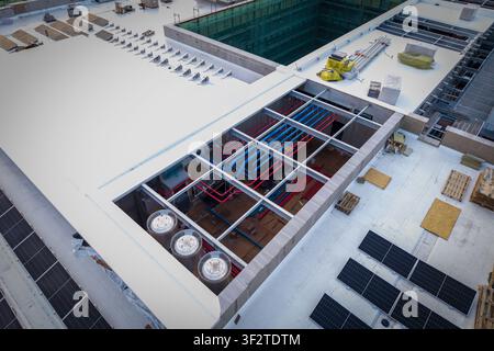 Aerial view of the ai data center cooling system featuring complex red and blue piping, industrial fans, and solar panels installed on a flat rooftop Stock Photo