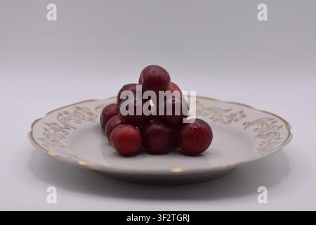Plate with overripe cherry plums on a white background. Isolated Stock Photo