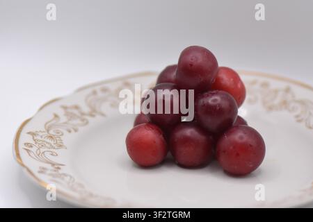 Plate with overripe cherry plums on a white background. Isolated Stock Photo
