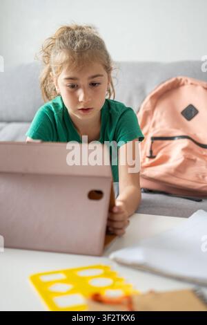 Focused schoolgirl using a tablet for online learning at home Stock Photo