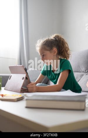 Focused schoolgirl using a tablet for online learning at home Stock Photo