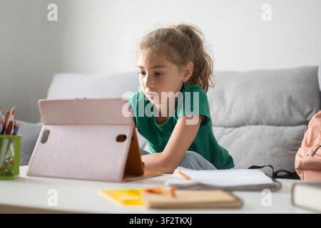 Focused schoolgirl using a tablet for online learning at home Stock Photo