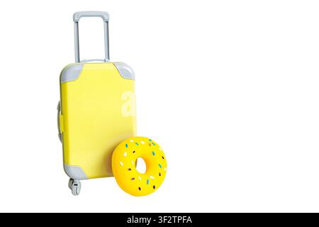 A yellow suitcase on wheels and a yellow swimming circle stand on a white wide background. Stock Photo