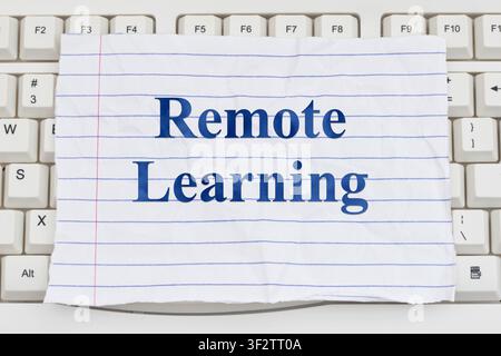 Remote Learning text on ripped lined paper on a white computer keyboard for online courses and e-learning Stock Photo