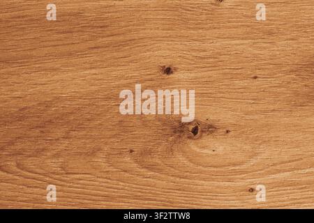 Horizontal close up overhead view of a warm golden brown wood texture with natural oak grain rings and rustic timber knots for vintage background desi Stock Photo