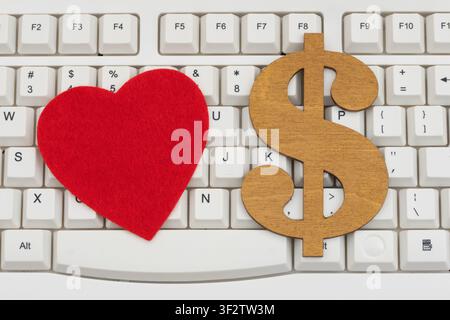 Blank red heart with a dollar sign on a white computer keyboard for online romance scams Stock Photo