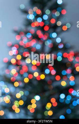 Vertical abstract Christmas background with colorful defocused lights on a decorated Christmas tree. Small blue, yellow, orange, red and green bokeh c Stock Photo