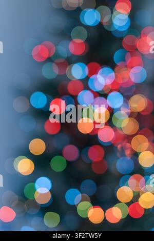 Vertical abstract holiday background with large colorful bokeh circles and the soft silhouette of a Christmas tree. Blue, yellow, orange, red and gree Stock Photo