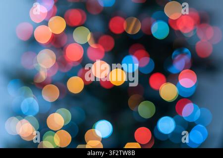 Vertical abstract Christmas background with colorful defocused lights on a decorated Christmas tree. Small blue, yellow, orange, red and green bokeh c Stock Photo