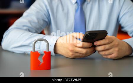 Cracked padlock and man with mobile phone, symbolizing cyber security breach, data protection risks, hacking, digital security, online privacy, and te Stock Photo