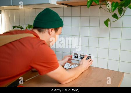 Professional electrician installing new electrical outlets in a modern kitchen, performing home renovation and electrical work for a household improvement project Stock Photo