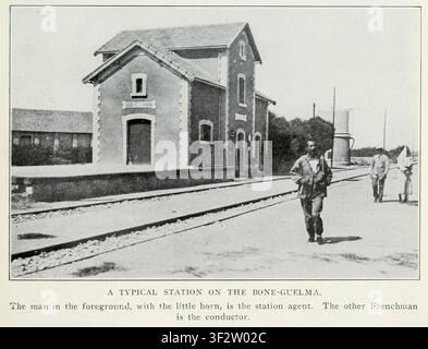 Station agent carrying a horn and a conductor walking on the platform and railway tracks, with the historic Sidi el Hani train station building visible in the background under a clear sky. From the Article THE RAILWAYS OF FRENCH NORTH AFRICA. By Edgar Allen Forbes From The Engineering Magazine Devoted to Industrial Progress Volume XXXVI October 1908 - March 1909 The Engineering Magazine Co. Stock Photo
