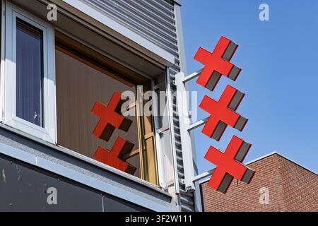Amsterdam, Netherlands, May 23, 2026. The iconic three red crosses of the Amsterdam coat of arms mounted on a modern grey office building with a refle Stock Photo