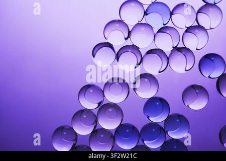 Clear gel spheres are creating an abstract texture on vibrant purple background Stock Photo