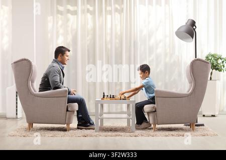 Father and son playing chess and sitting in armchairs Stock Photo