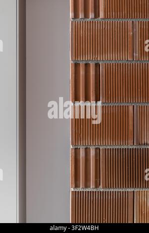 Textured brown ribbed brick wall with warm earthy tones, close architectural surface detail, vertical pattern, subtle relief, and contemporary Stock Photo