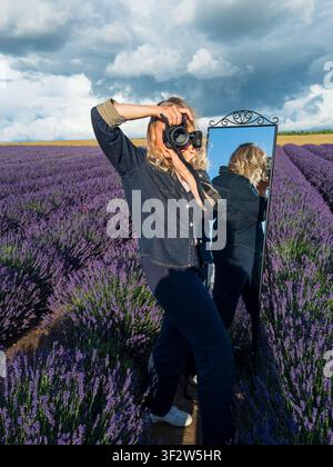 Portrait of Female Photographer Taking Photos in a Lavender Field Under Dramatic Blue Storm Sky.. Stock Photo