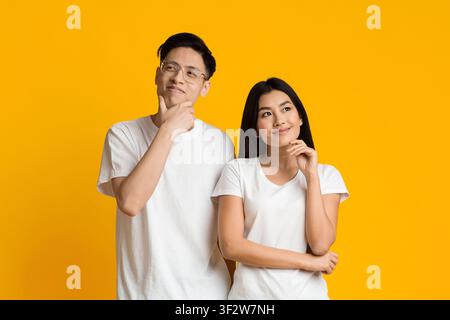Young asian couple day dreaming on yellow background Stock Photo