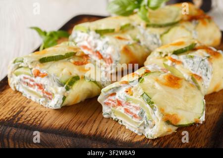 Close-up of sliced ??zucchini roll stuffed with salmon and cream cheese on a wooden board on the table. Horizontal Stock Photo