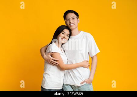 Asian sweet couple embracing over yellow background Stock Photo