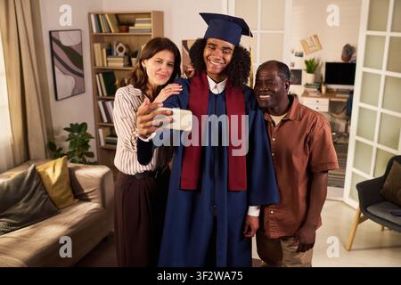Black Teenage Graduate Taking Family Selfie at Home Celebration Stock Photo
