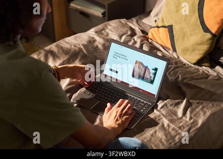Man Browsing Real Estate Listings on Laptop at Home Stock Photo