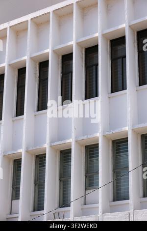 Minimalist architectural detail featuring a modern white building facade with repetitive windows and geometric concrete lines. Stock Photo