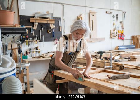 Professional craftsman working on restoration of antique wooden door at workbench in carpentry Stock Photo