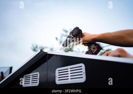 Man installing roof panel using cordless power drill Stock Photo
