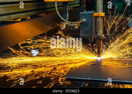 CNC laser cutting machine cutting metal sheet with flying sparks Stock Photo