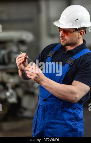 Industrial worker measuring metal part with caliper in manufacturing plant Stock Photo