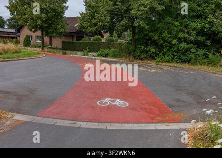 Red asphalt bicycle lane curving through a residential street in Coesfeld, Germany Stock Photo