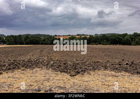 Newly ploughed dark soil field with stubble under a dramatic cloudy sky in Coesfeld, Germany Stock Photo