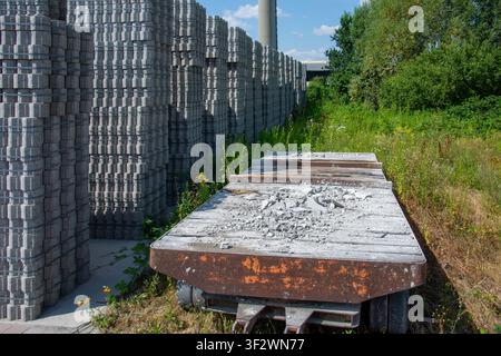 Industrial manufacturing yard with rows of stacked concrete paving blocks and an old trailer platform with cement debris in Coesfeld, Germany Stock Photo