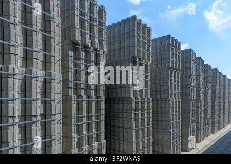 Rows of grey concrete paving blocks secured with packaging straps under a blue sky in Coesfeld, Germany Stock Photo
