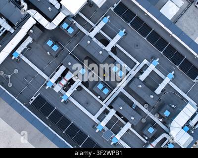 Aerial view of a modern industrial rooftop featuring extensive HVAC ventilation systems, cooling units, and integrated solar panel arrays in Krakow, L Stock Photo