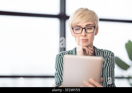 Successful Middle-Aged Businesswoman Using Laptop Sitting At Workplace Indoor Stock Photo
