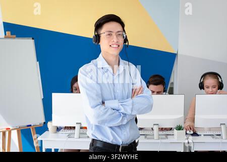 Portrait of Asian male helpdesk operator posing and smiling at call centre Stock Photo