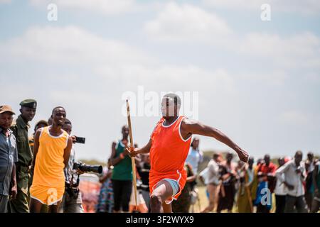 Kajiado County, Kenya - 14 December 2024: View of a man in an orange athletic uniform holding a spear during Maasai Olympics at Amboseli National Park Stock Photo